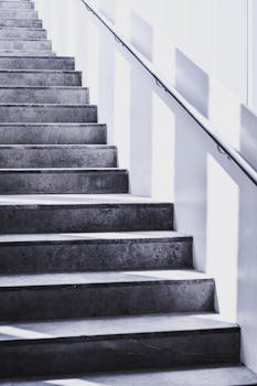 pexels-photo-921025-921025 A contemporary concrete staircase with sleek steel railing and natural light casting shadows.